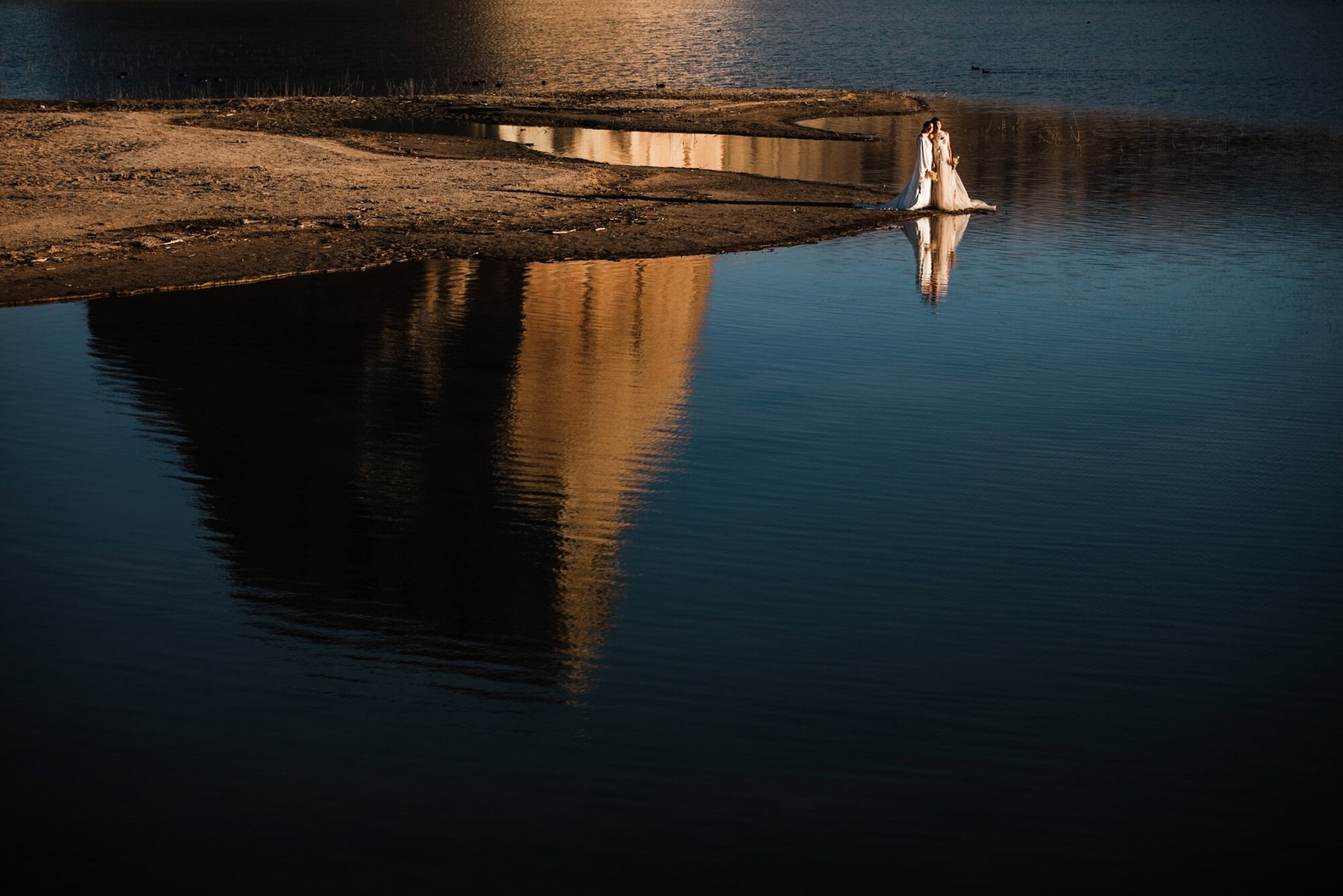 newlyweds hugging at the edge of lake powell. 
