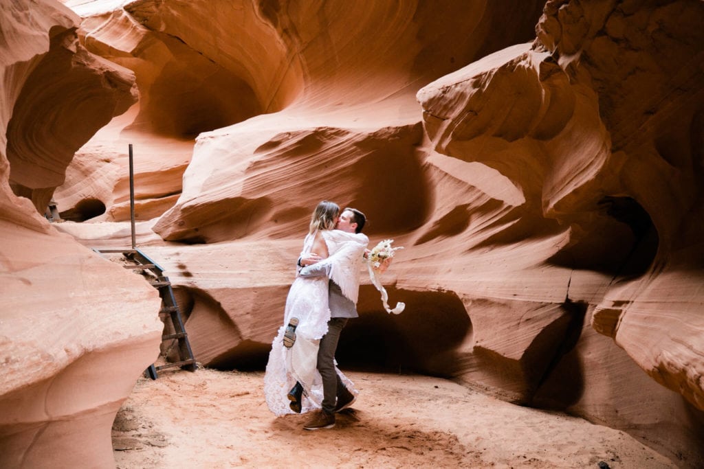 The bride and groom dancing in a slot canyon on their wedding day. Having just eloped, it's just the two of them in the smooth, red canyon.