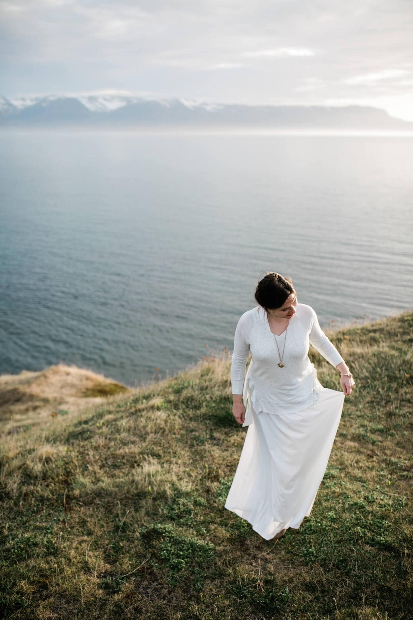 A bride plays with her skirt on a sea cliff in Iceland.