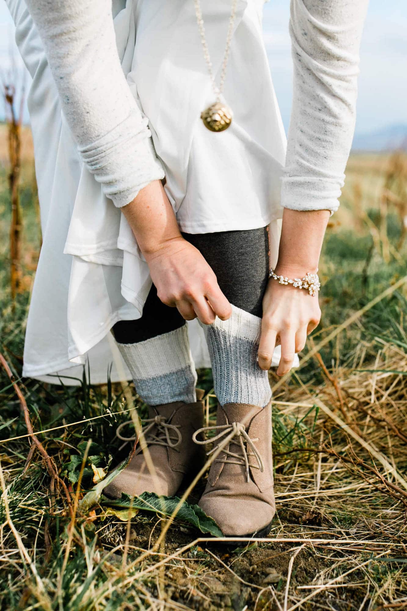 An adventure bride fixes her socks in an Iceland field.