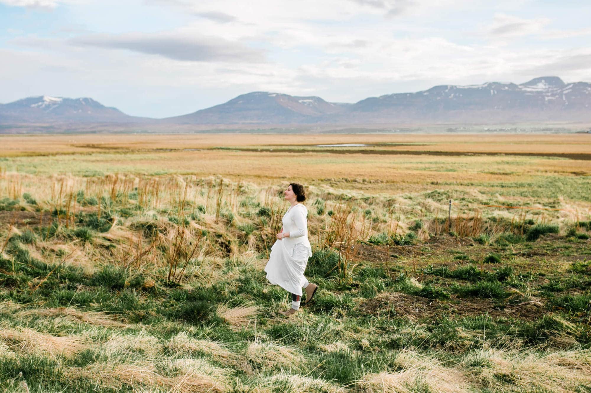 An adventurous bride walks through a field before her elopement.