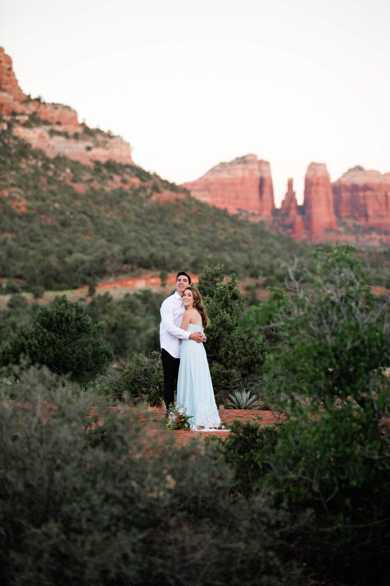 Wrapped in each others arms the bride and groom take in the beautiful red rocks around them.