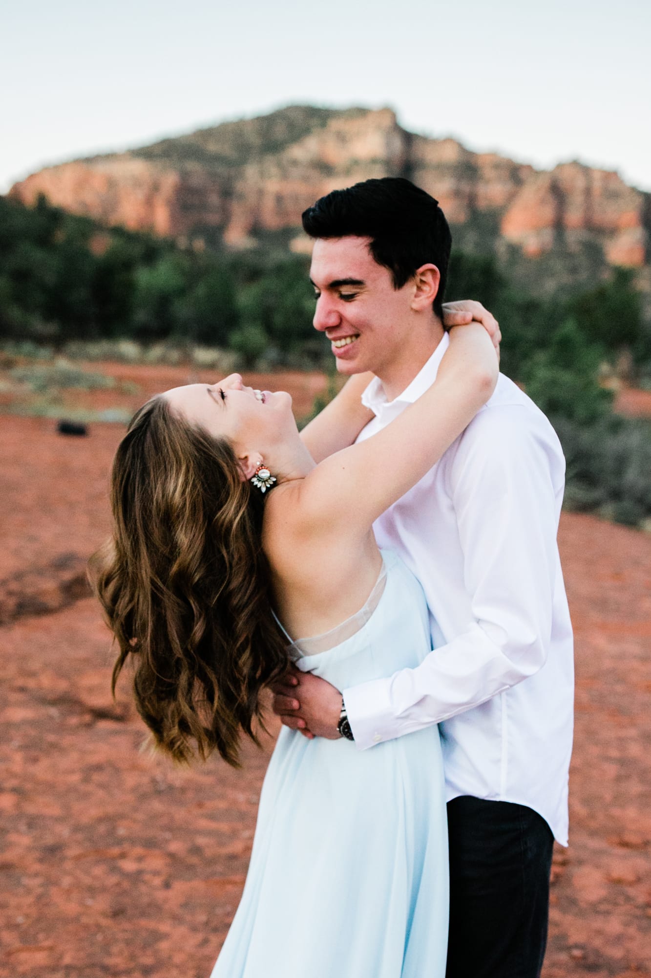 While hugging her groom, the bride throws her head back with joy during their Sedona Adventure Wedding.