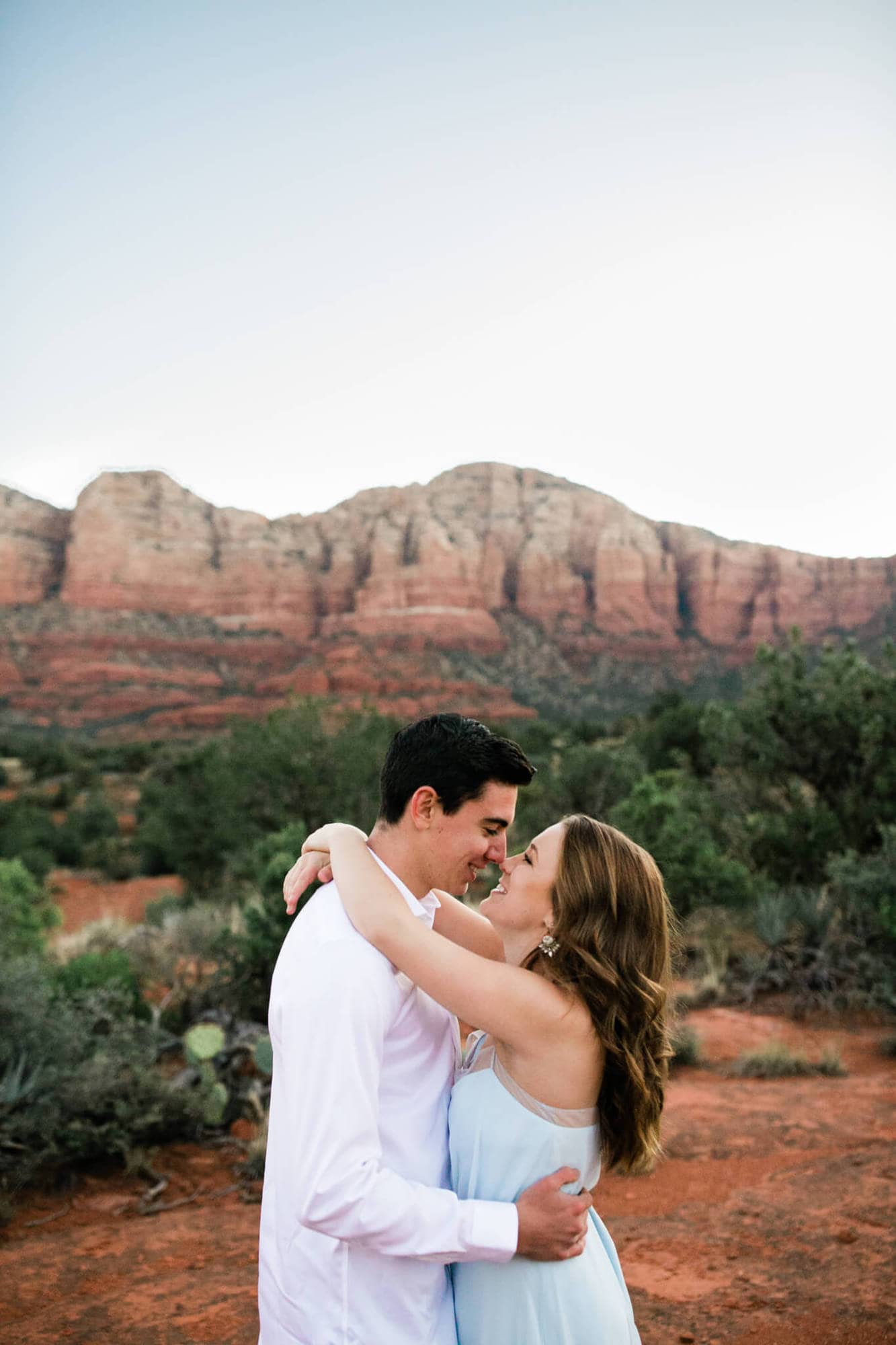 Cute bride and groom touch noses on their elopement day. The famous red rocks of Sedona frame the couple perfectly.
