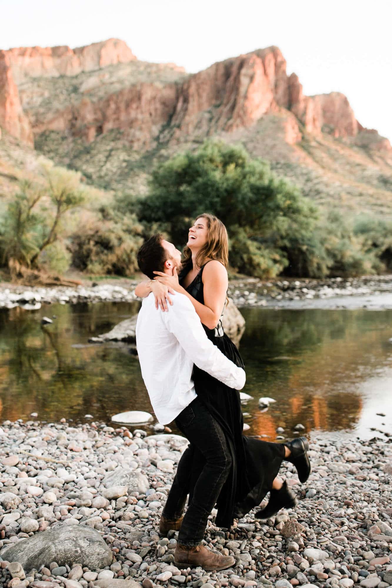 The couple walks along the Salt River during their desert engagement session.
