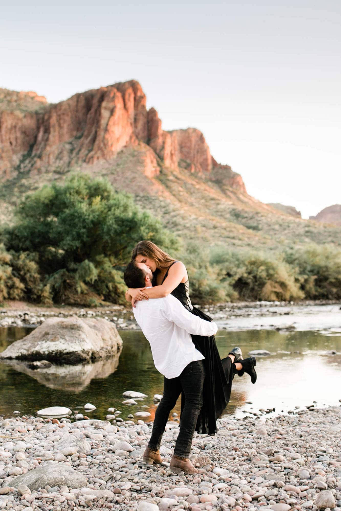 Groom picks up his bride as they play on the shores of the Salt River.