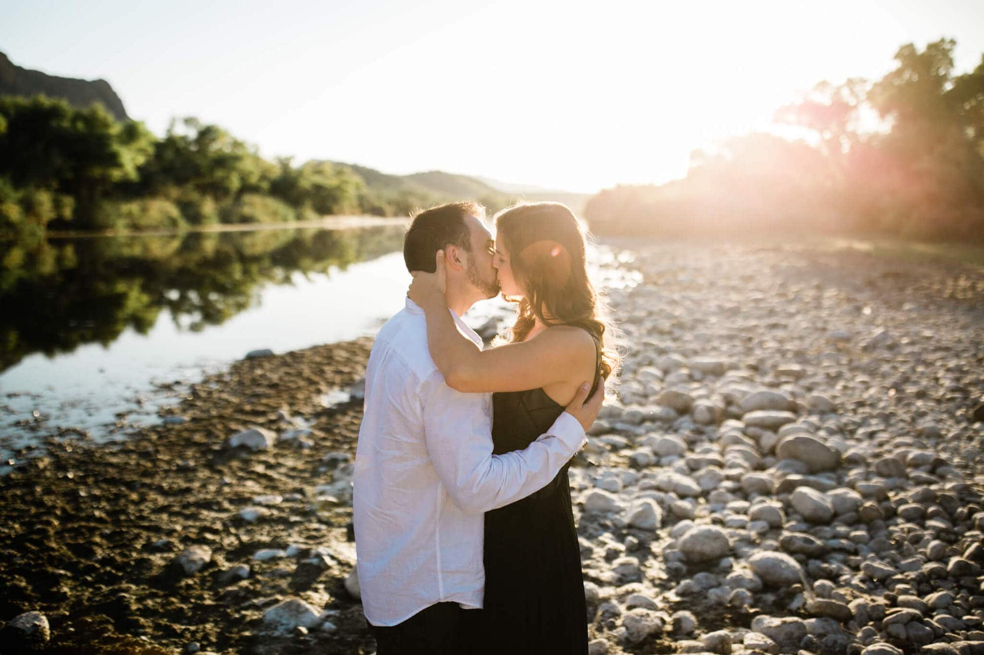 Logan and Nicole kiss with the Salt River winding into the distance behind them, the sun low on the horizon.
