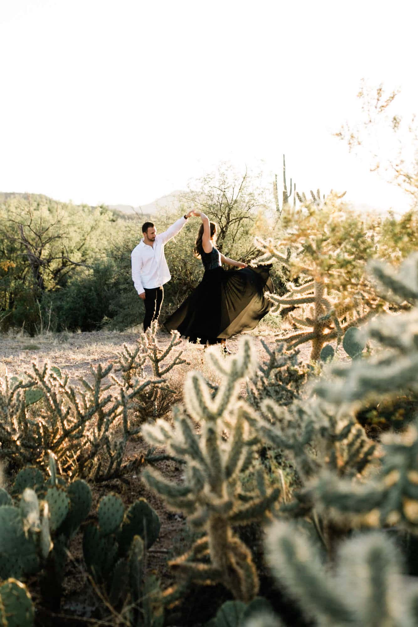 Logan and Nicole dance among the cactus during their adventure session.
