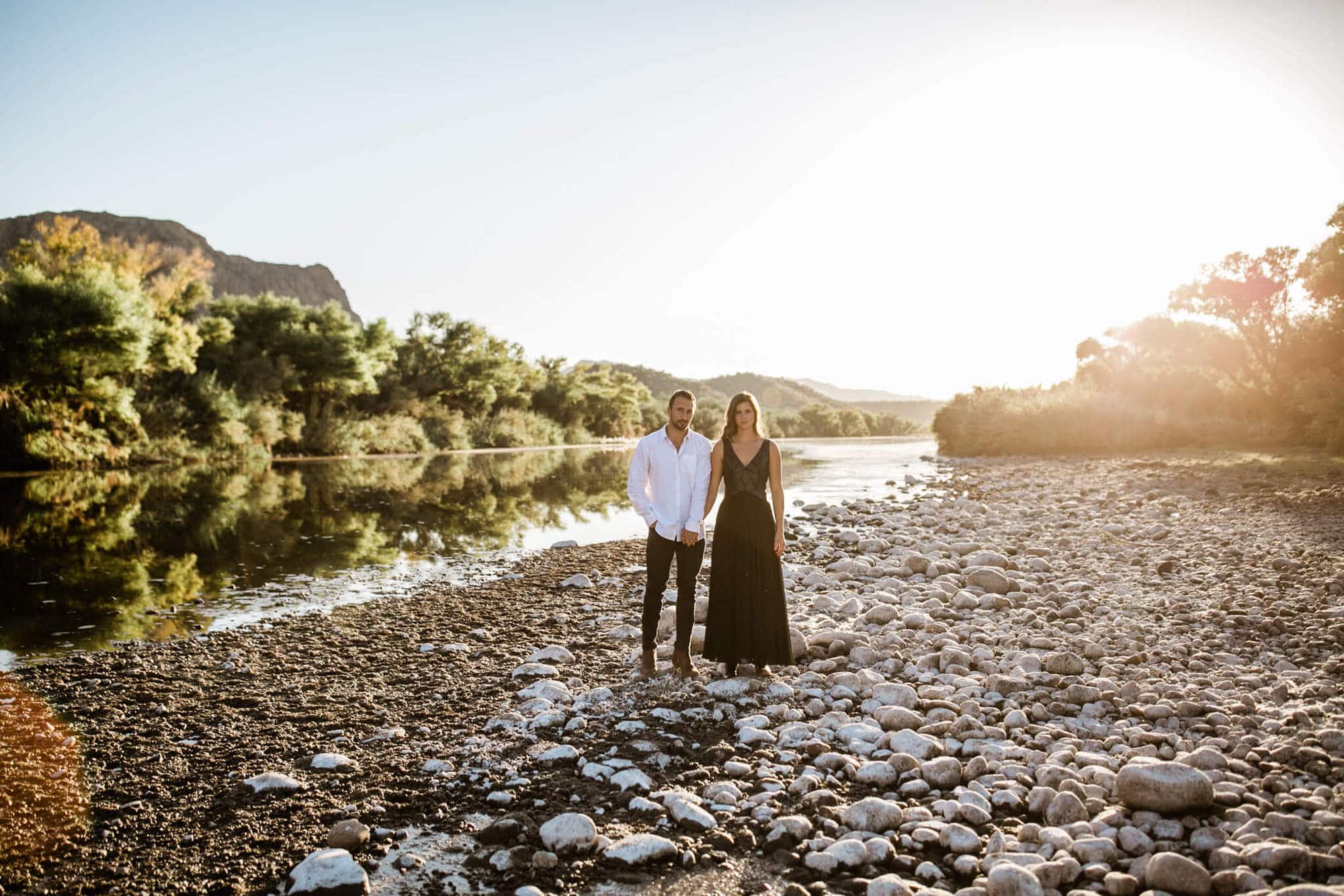 The adventurous couple stand hand in hand with the Salt River extending behind them.
