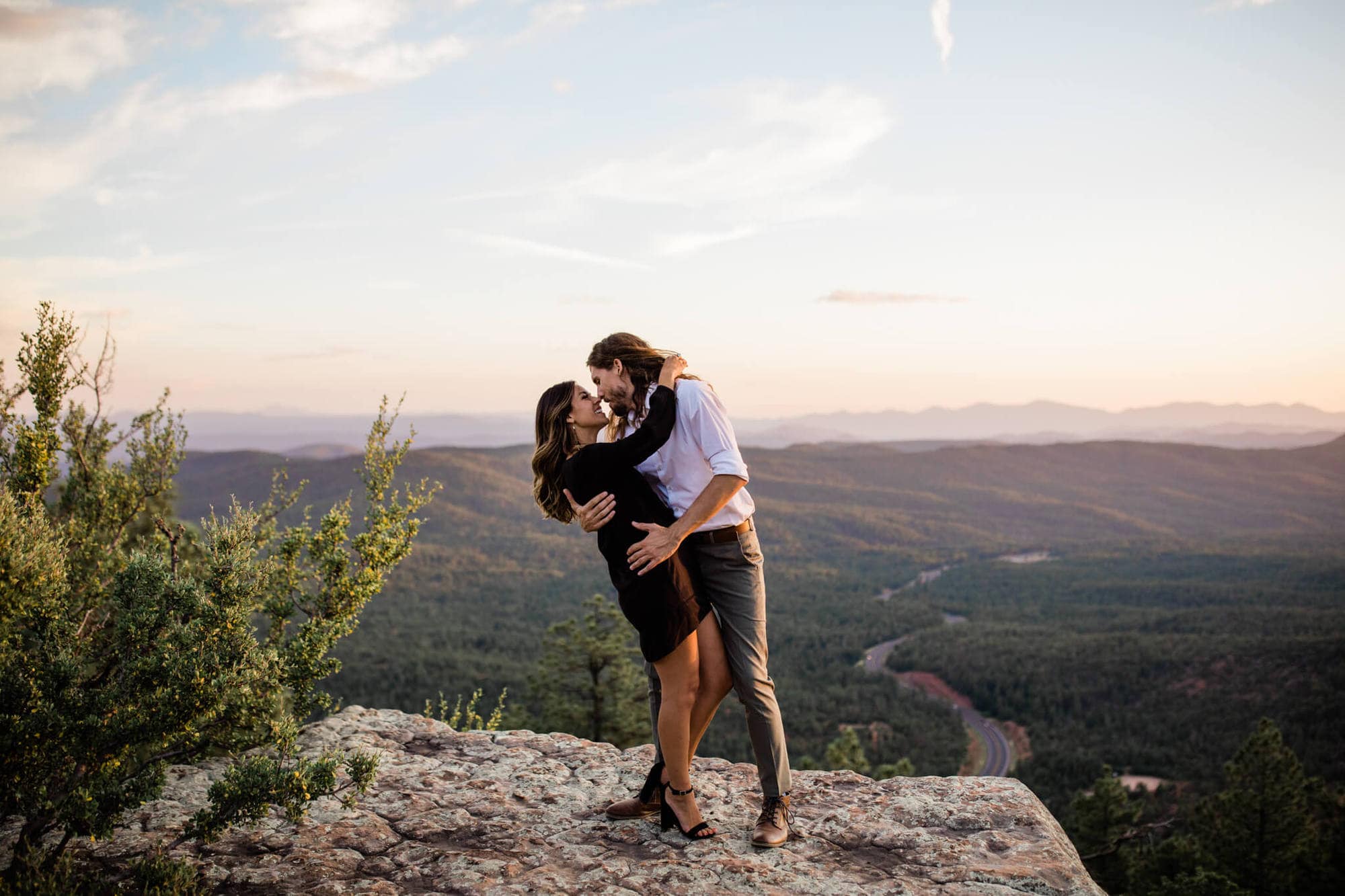 David dips Leah at the edge of the Mogollon rim during their forest engagement photos. it is the perfect spot for adventure and forest vibes.