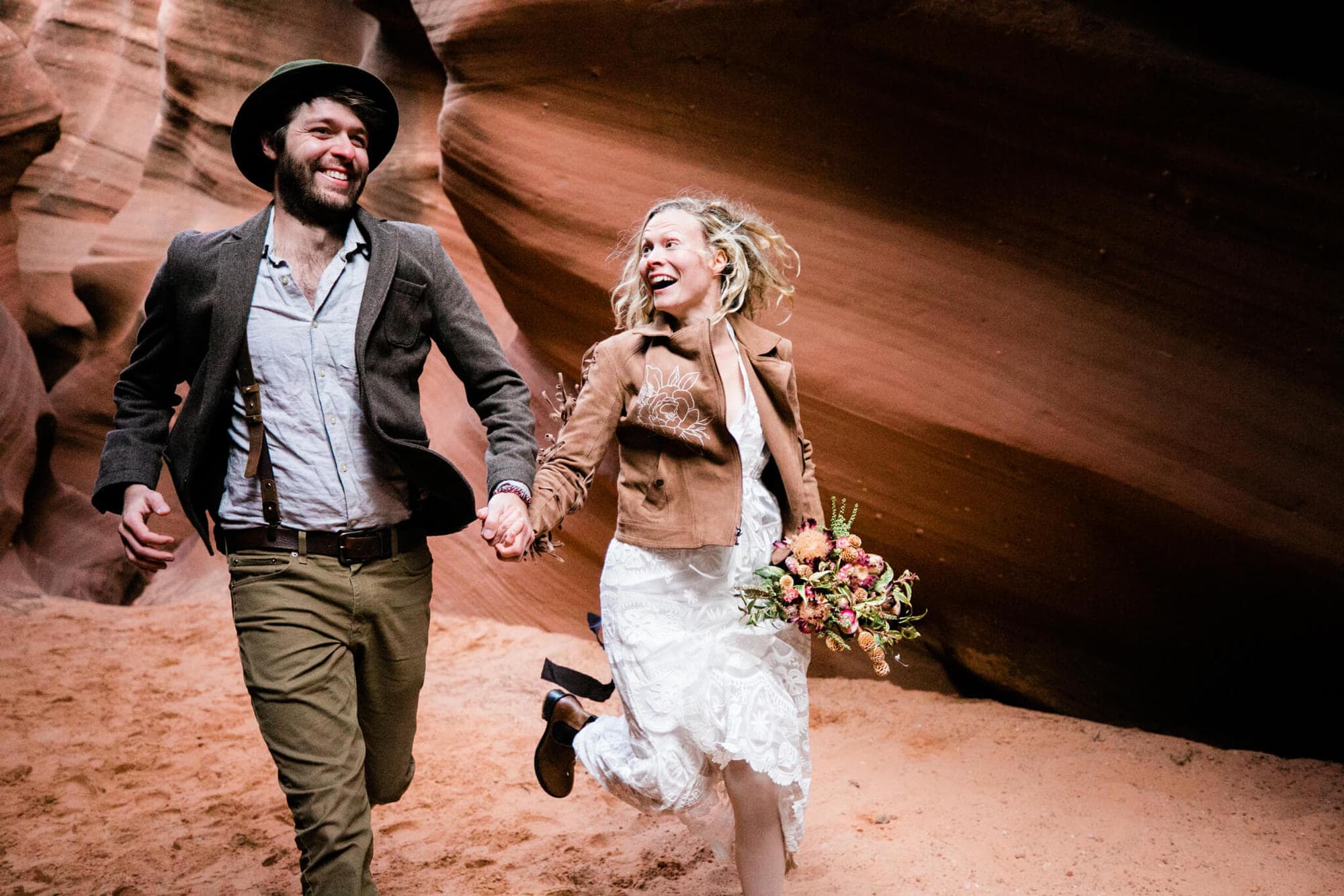 A joyous, adventerous couple runs through a slot canyon on their elopement day.