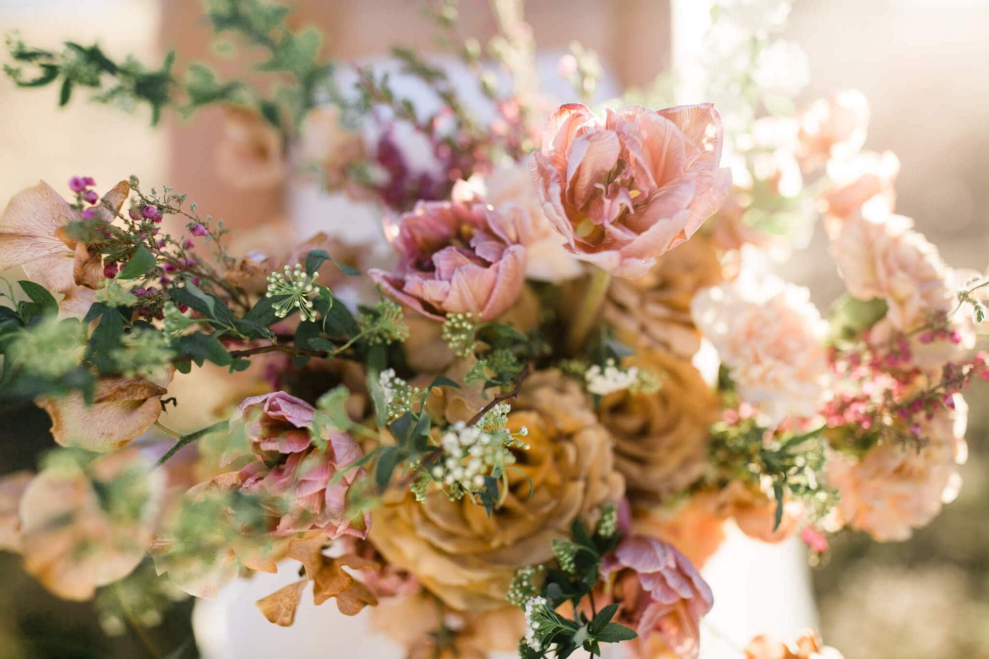 A closeup of  the brides bouquet made up of pink, peach, and copper flowers.
