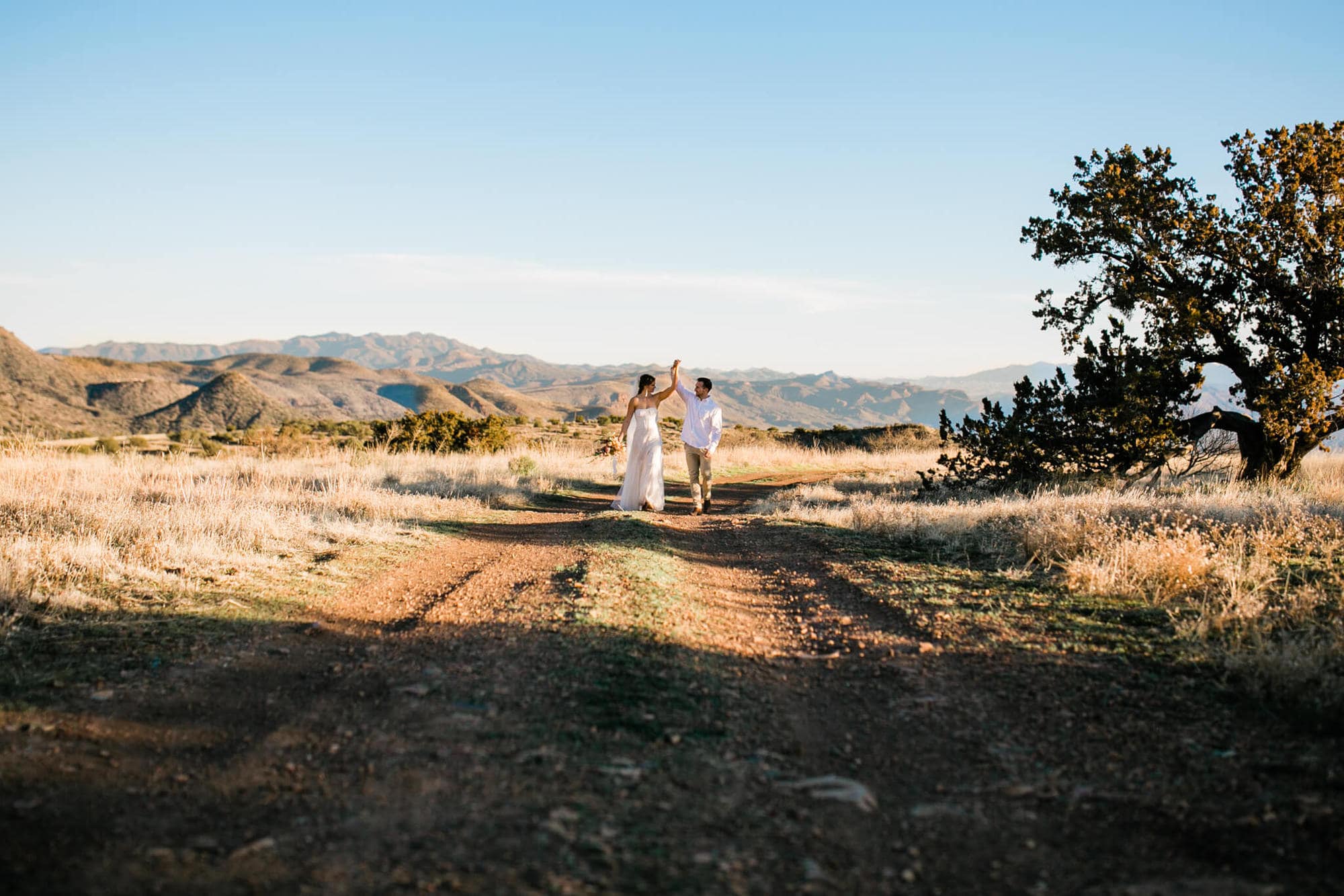 The bride and groom walk up the mountain dirt road and dance.