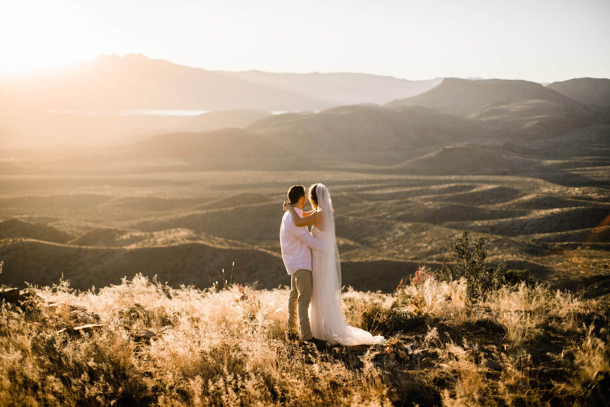 During their elopement in the desert, the bride and groom look out into the sunlit valley before they say their vows.