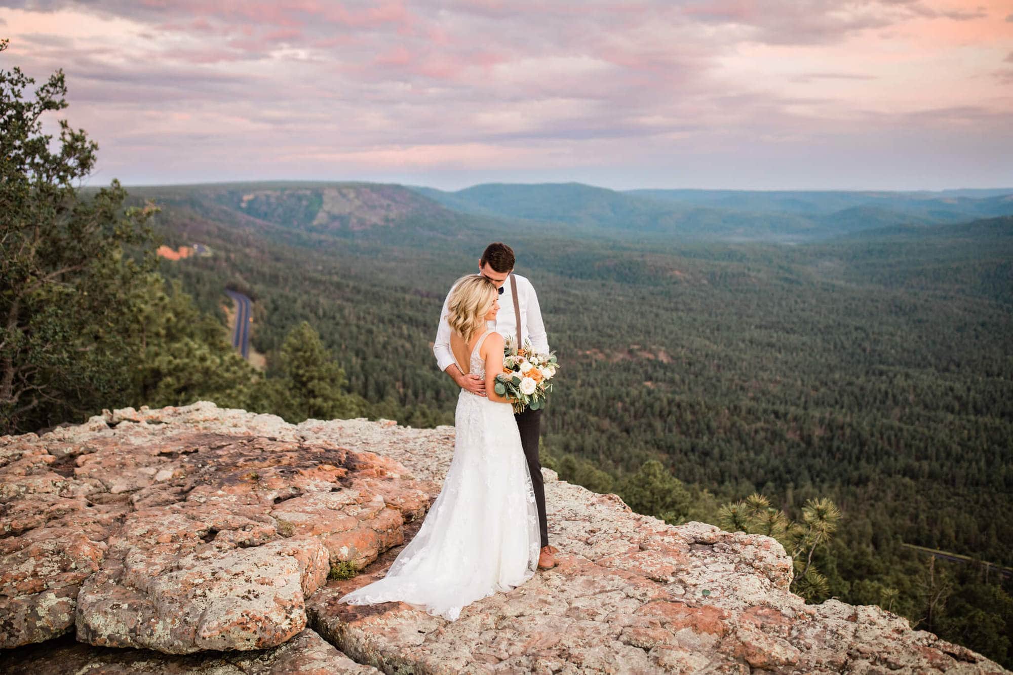 Eloping couple hugs at the edge of the Mogollon Rim at sunset.