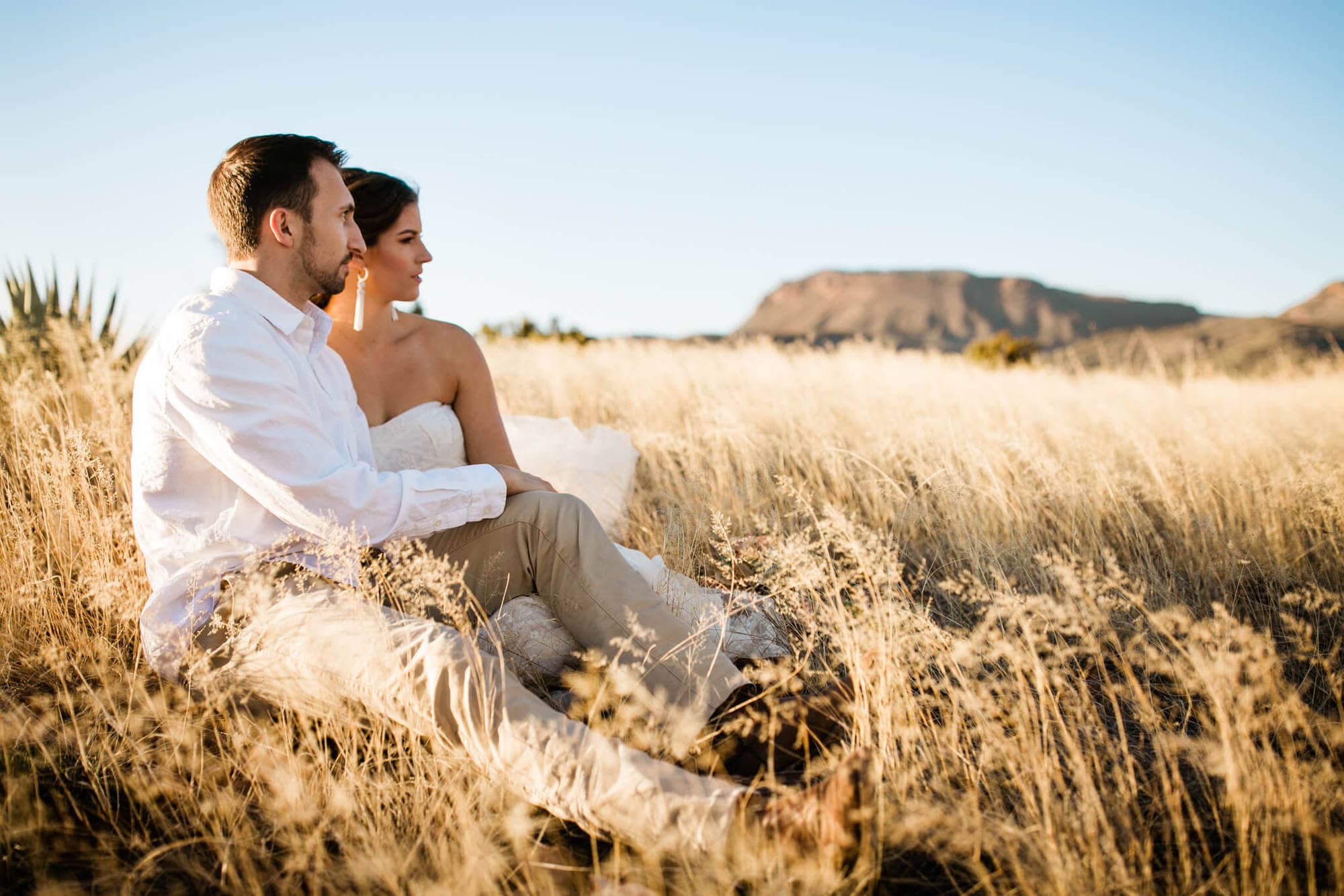 Couple sits in a golden field outside of Phoenix. 
