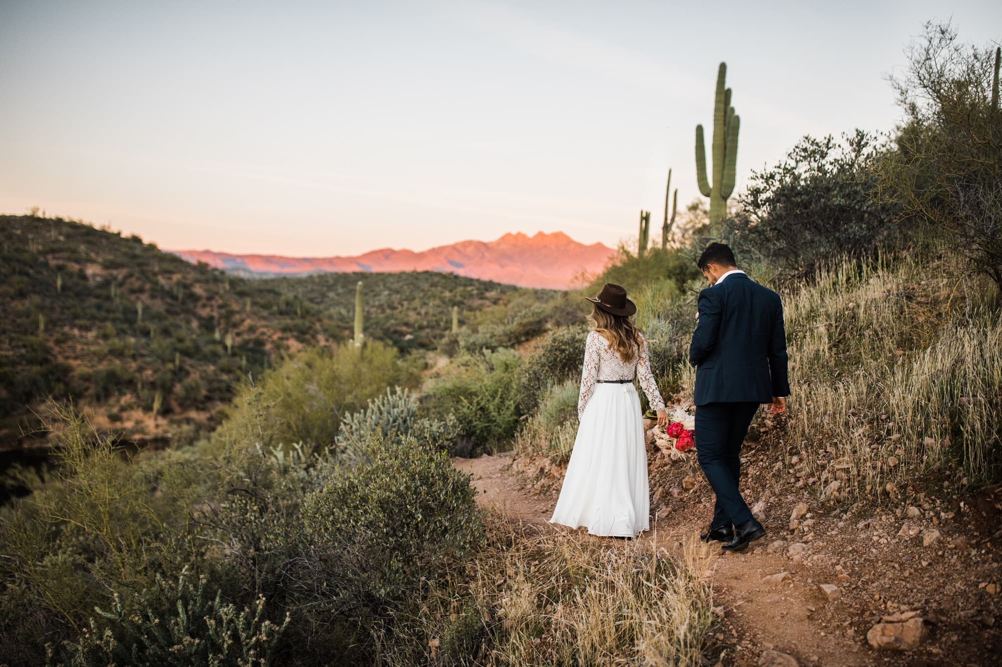 The couple elopes in Phoenix and walks in the desert at sunset.