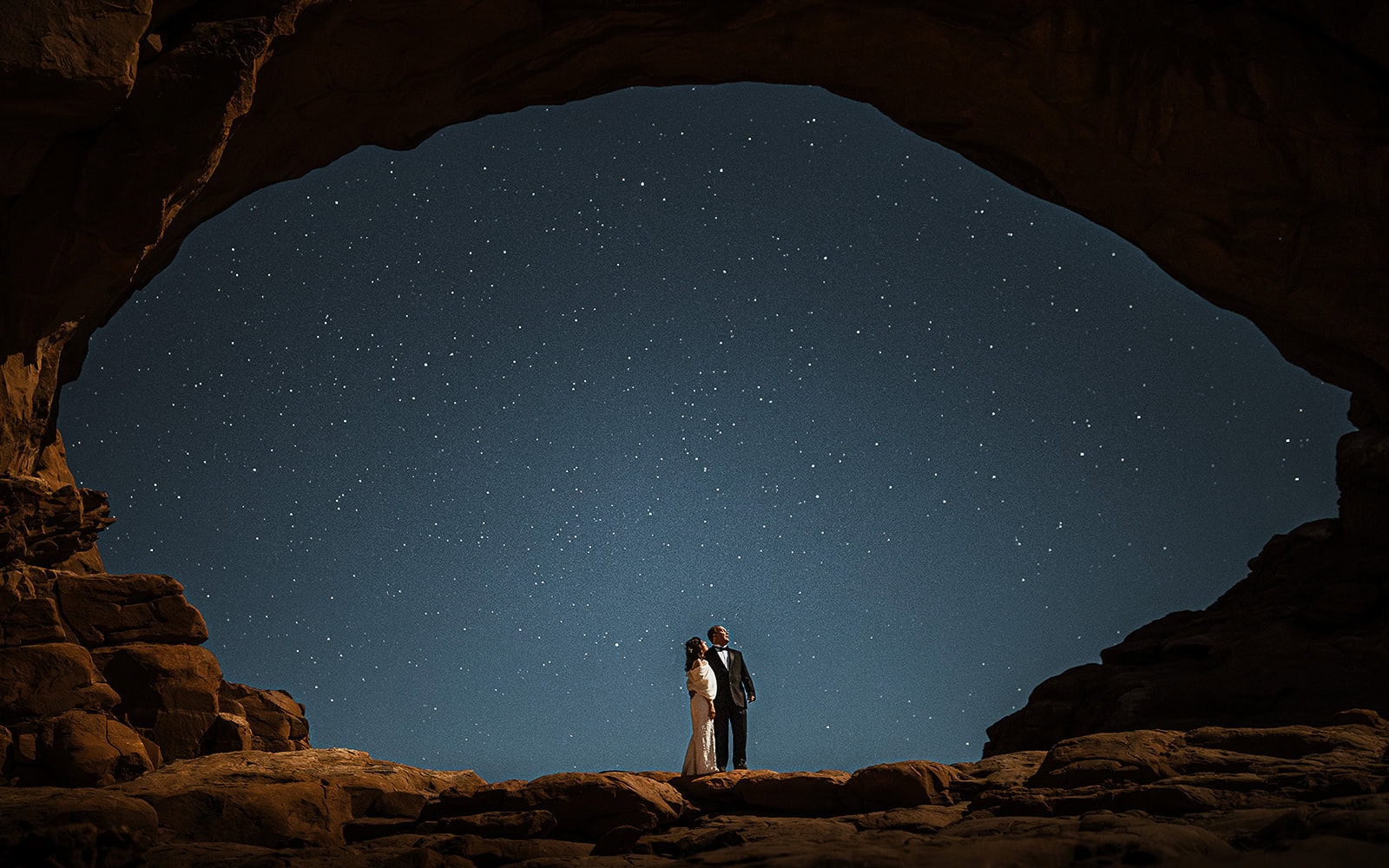 newlyweds standing under an arch with stars shining overhead.