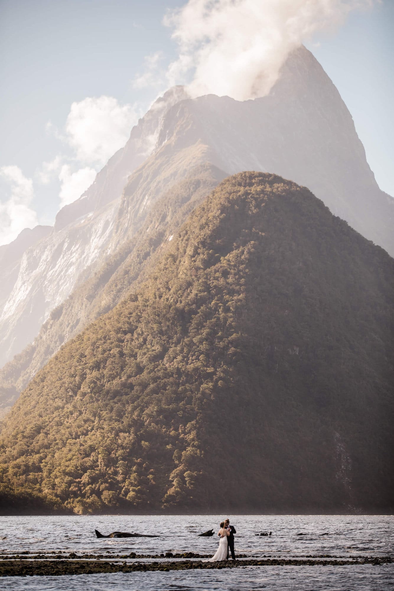 A tiny bride and groom hug in front of Mitre Peak during their Milford Sound elopement. 