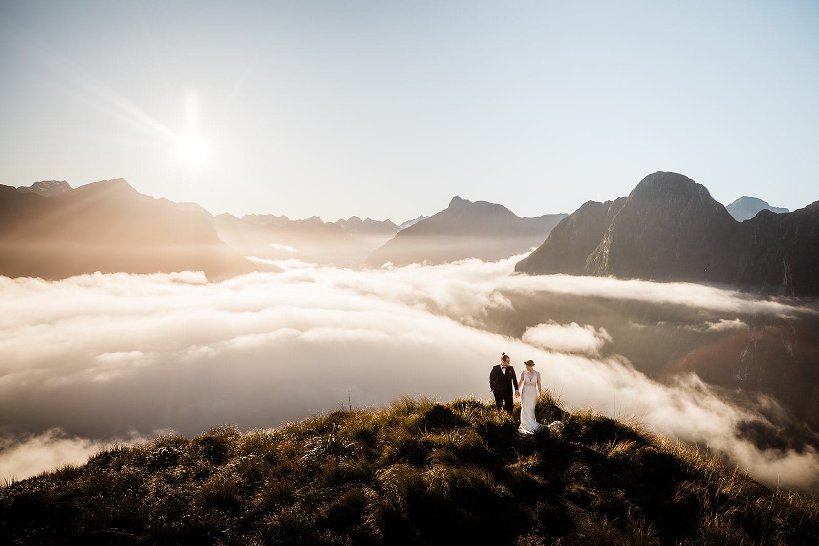 Bride and groom hold hands while walking around Mitre Peak during their Fjordland National Park elopement in New Zealand