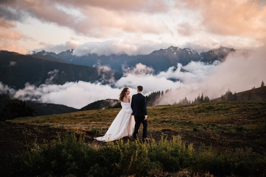 Bride and groom hold hands as they walk across Hurricane Ridge during their Olympic National Park elopement