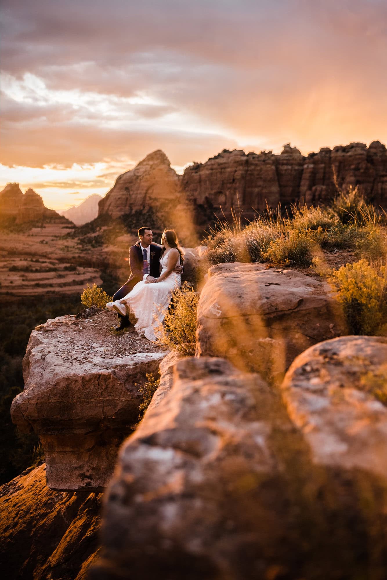 newlyweds sitting on red rocks soaking in the scene outside of sedona.