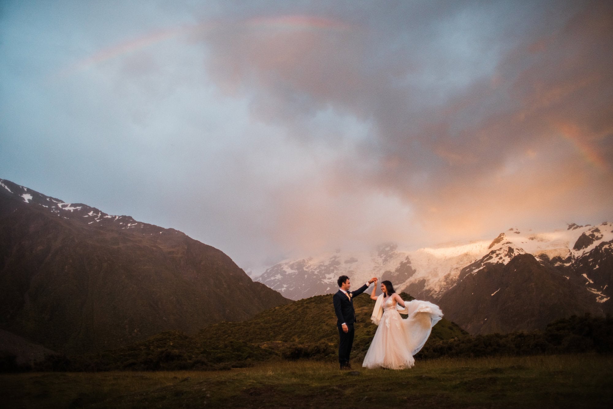 Bride and Groom dance under a rainbow at sunrise during their New Zealand elopement.
