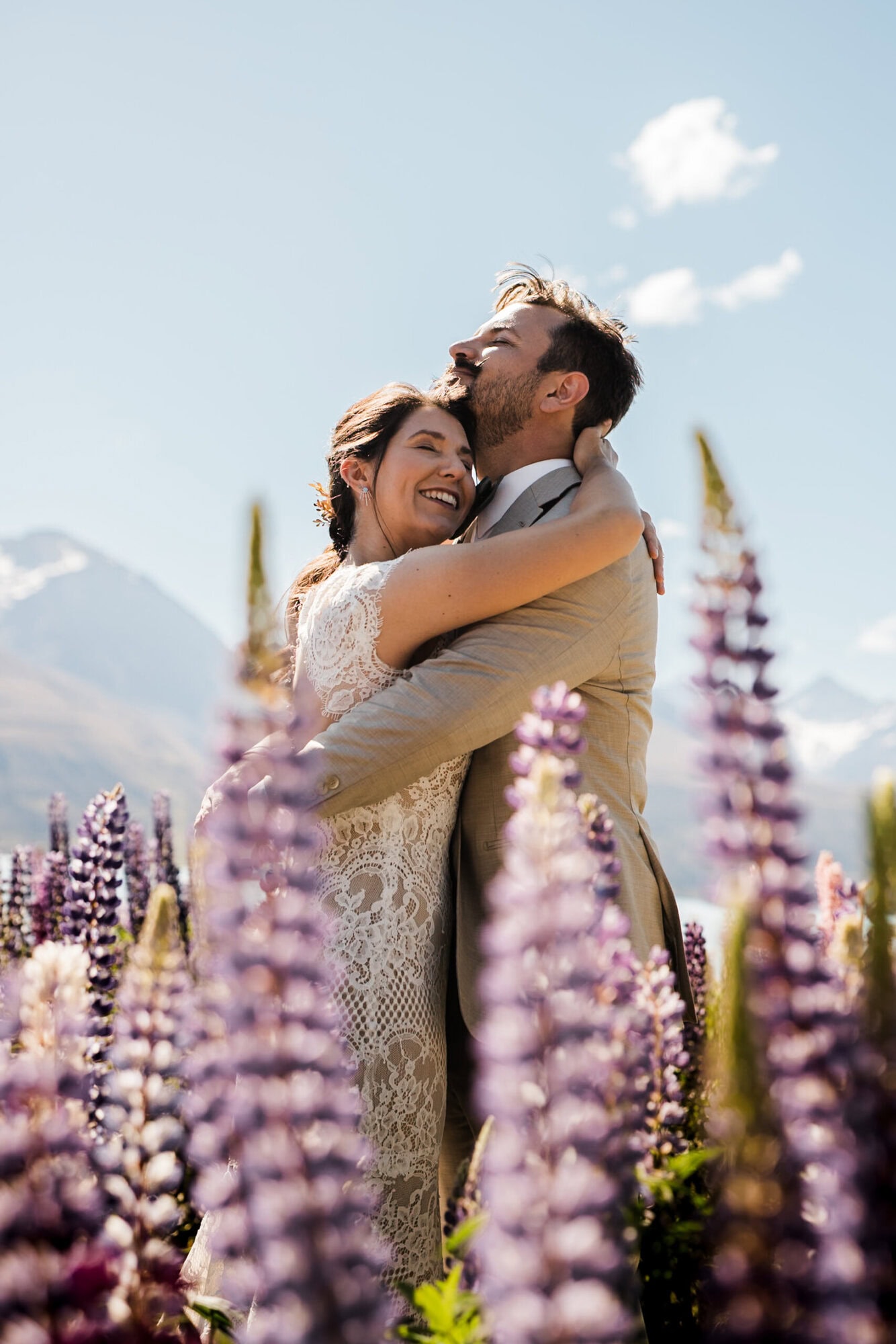 A bride and groom embrace in a field of flowers on their elopement day.