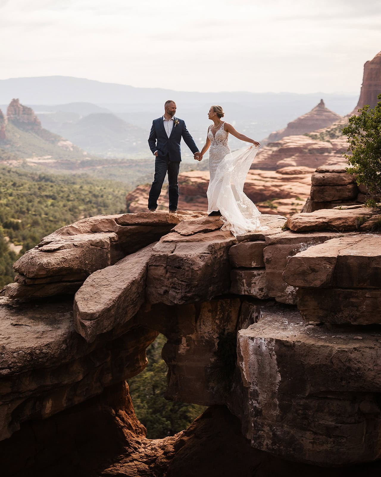 Newlyweds holding hands at an expanisve viewpoint in Sedona.