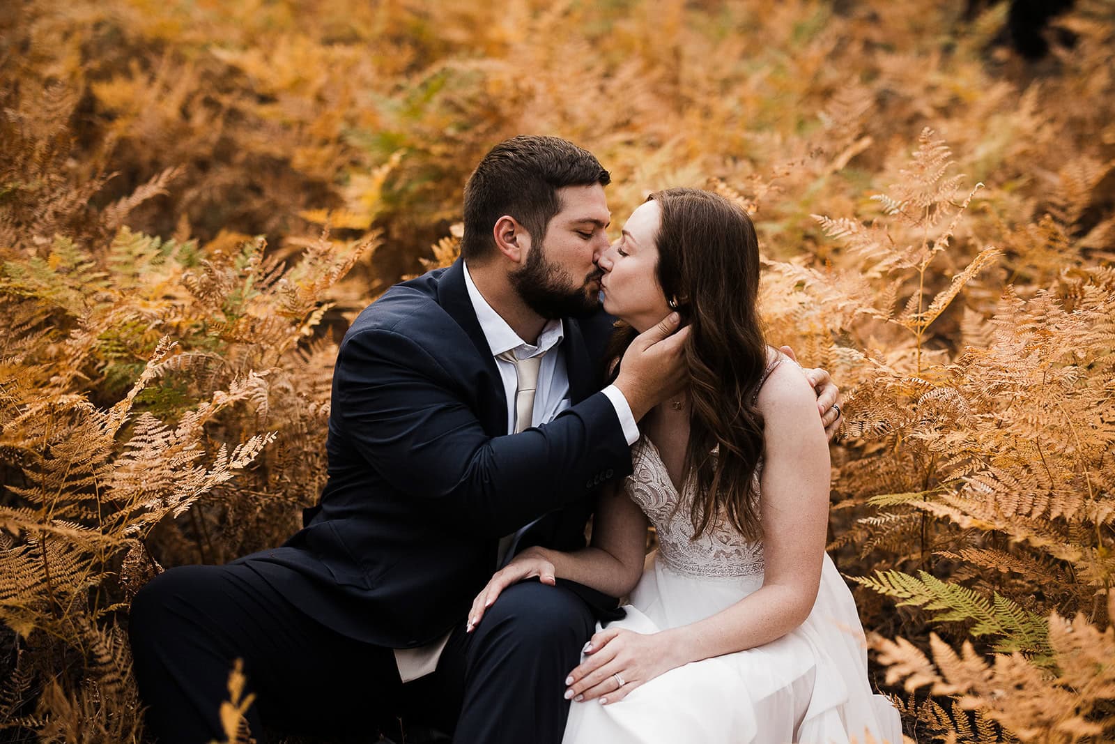newlyweds kissing in a field of golden ferns during their flagstaff elopement.