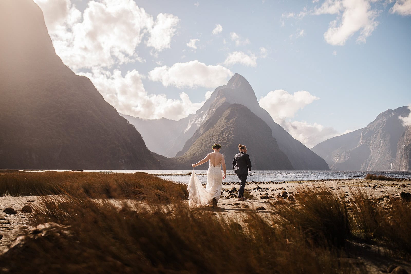 newlyweds walking along the beach in Milford Sound in New Zealand, one of the best winter elopement destinations.