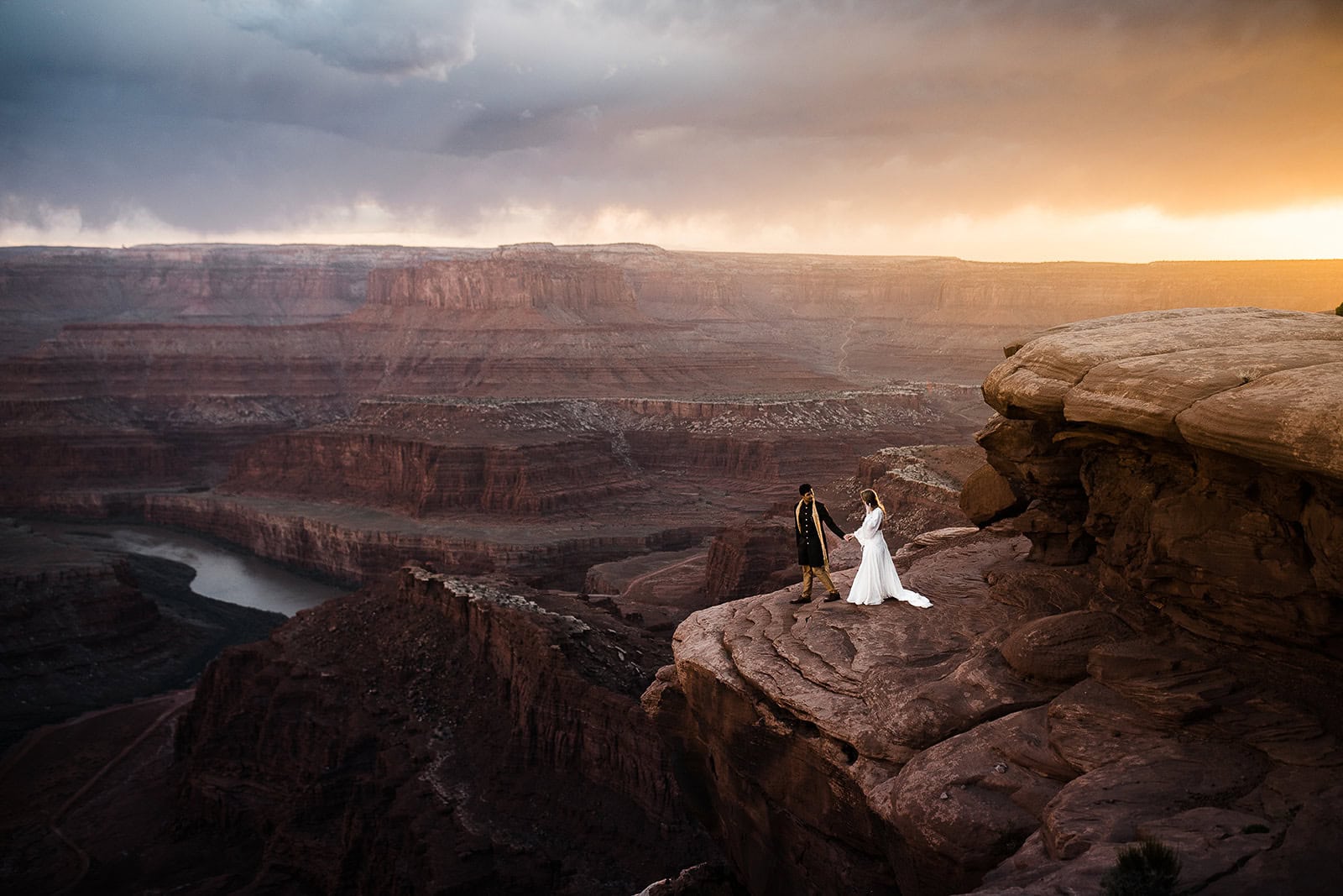 newlyweds enjoying the views at the edge of a canyon at sunset.