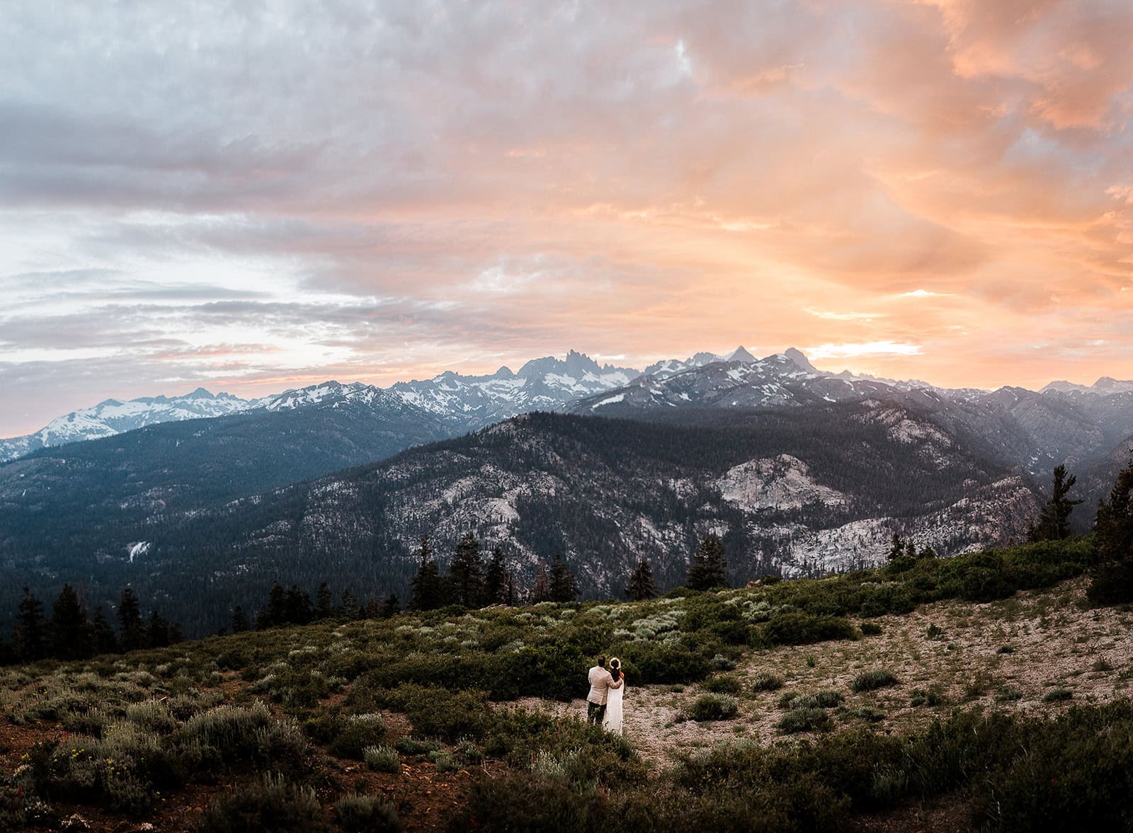 newlyweds enjoying the view of the mountains at sunset. 