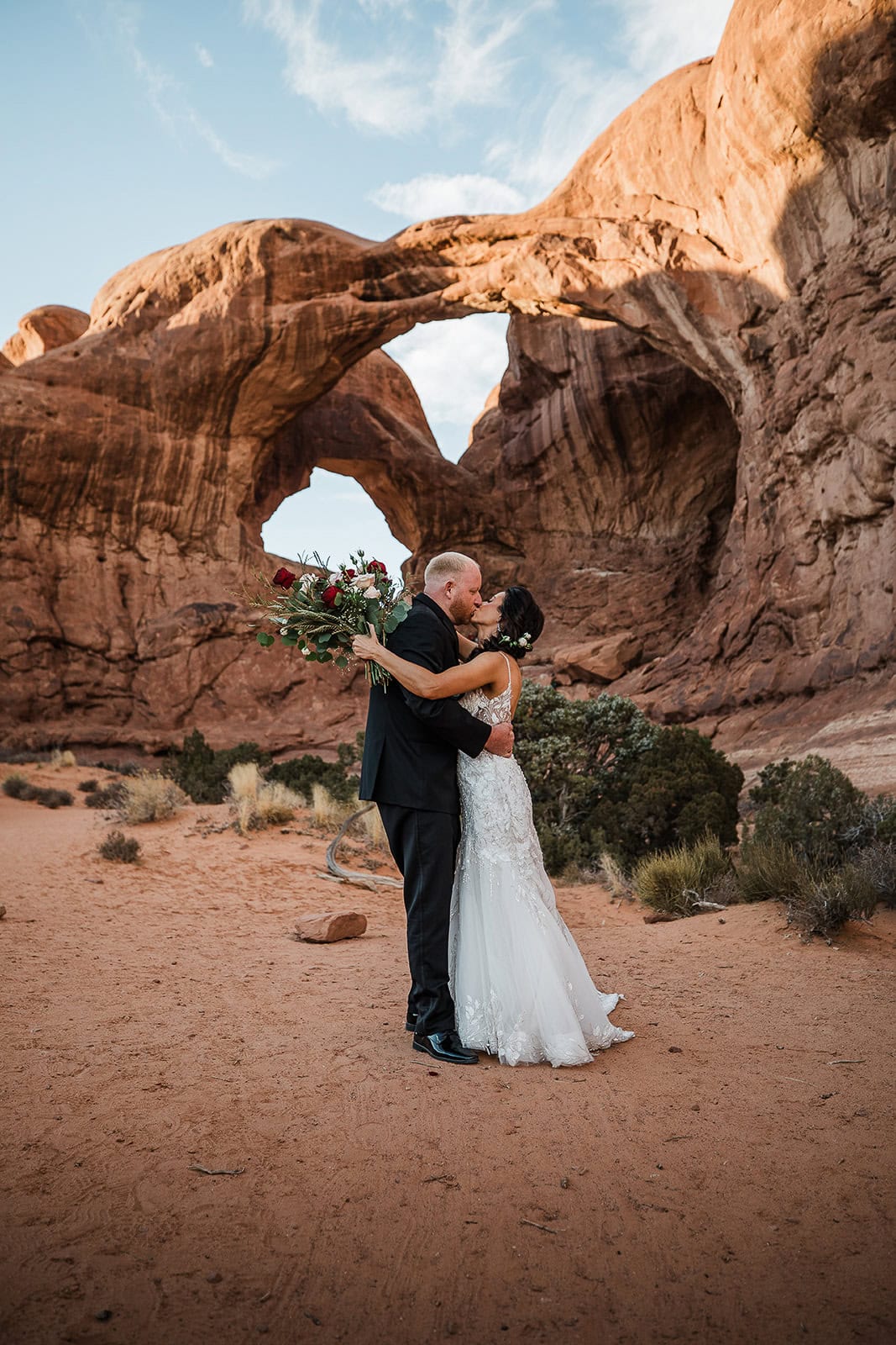 newlyweds kissing in front of double arch, one of the places to elope in Moab.