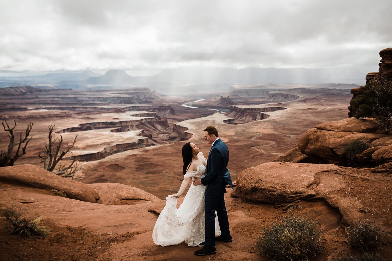 newlyweds hugging at the edge of a canyon in moab in winter, one of the best seasons to consider when deciding when to elope in Moab.