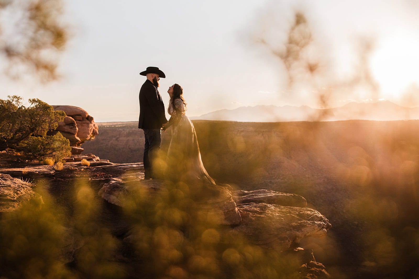 Newlyweds holding hands at the edge of a canyon in fall, one of the best seasons to consider when deciding when to elope in Moab.