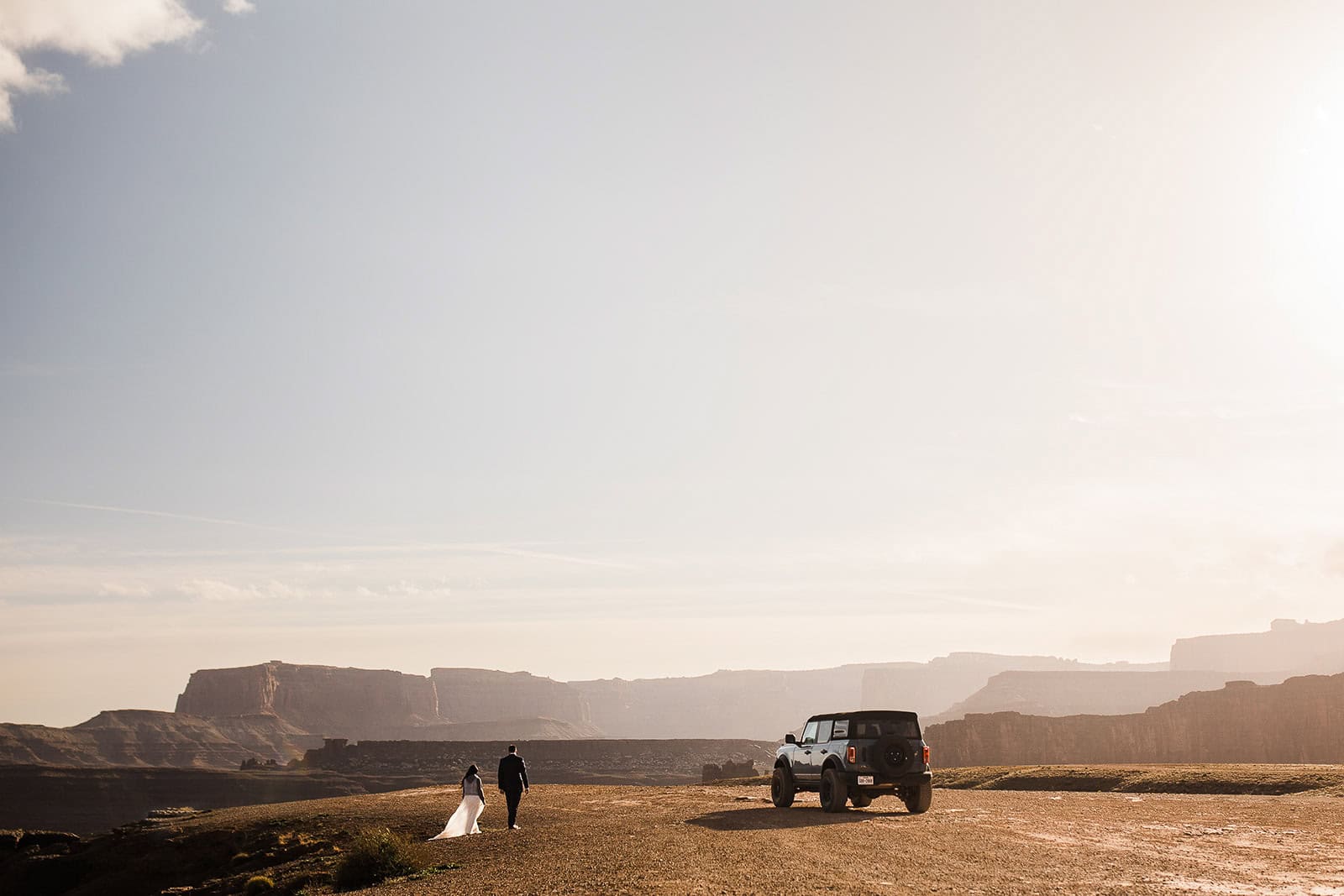 newlyweds walking next to a rental jeep, an expense you consider when answering the question "how much does it cost to elope"?