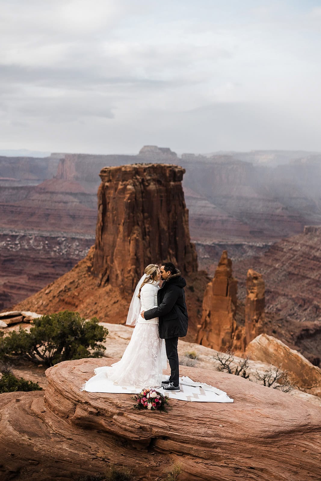 newlyweds kissing on a cliffside in utah.