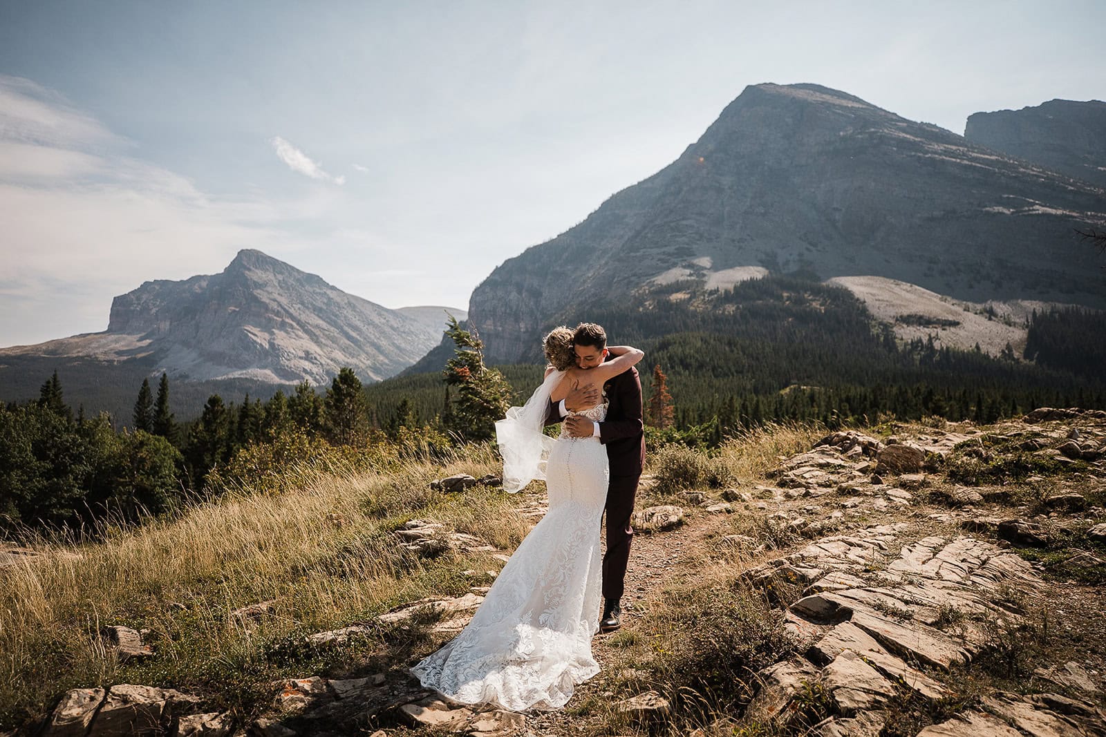 newlyweds hugging in front of a mountainside.