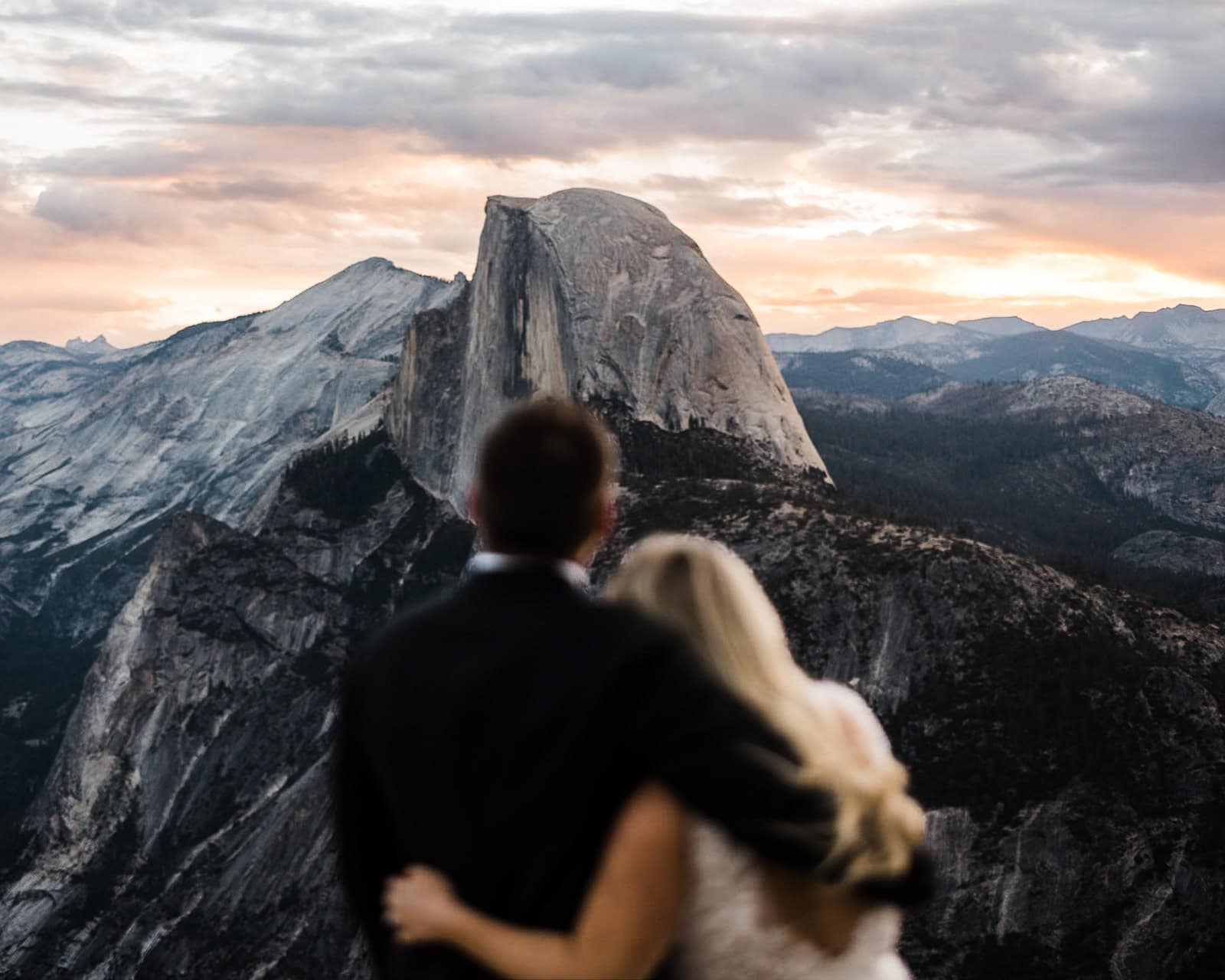 newlyweds hugging in front of Half Dome at Glacier Point, one of the best Yosemite wedding locations.