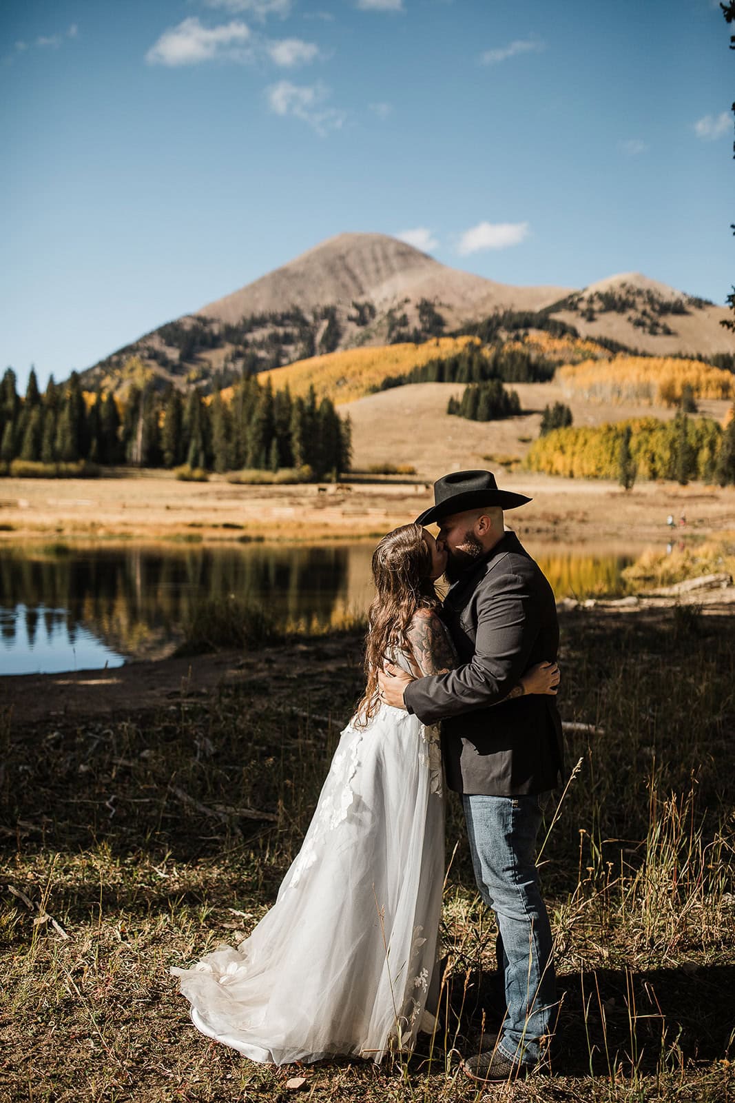 newlyweds hugging with a lake and mountains in the background during their wedding in the La Sal Mountains.