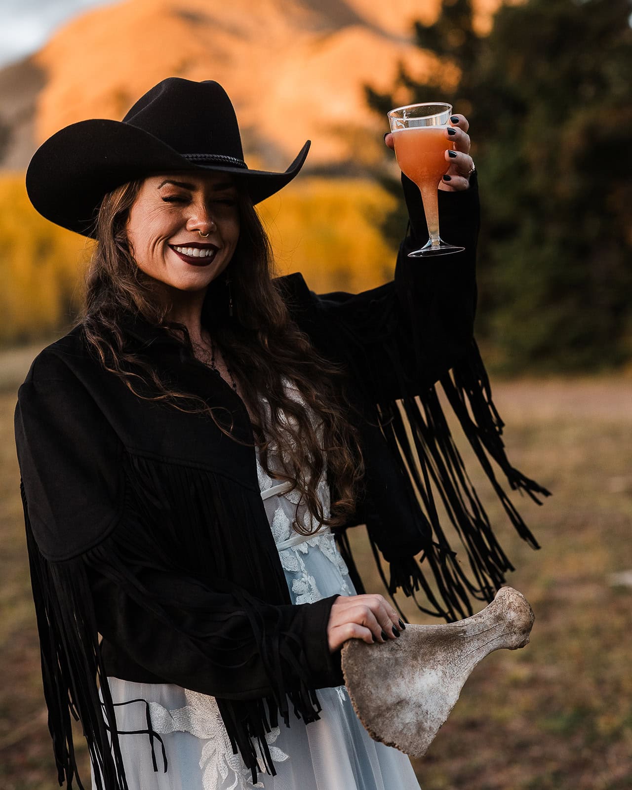 the bride holding a bone and a drink wearing a jacket with fringes.
