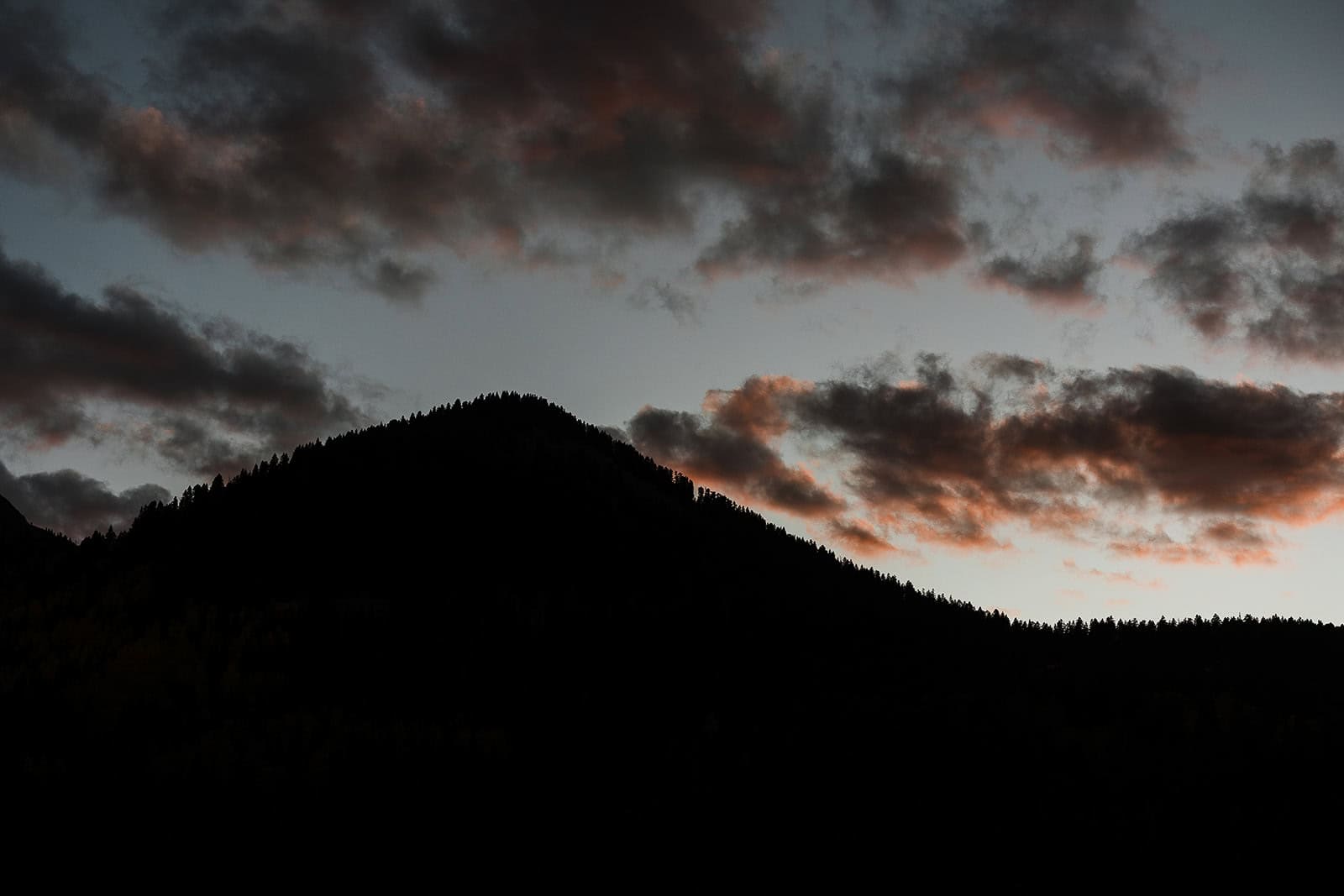 the silhouette of a mountain at dusk.