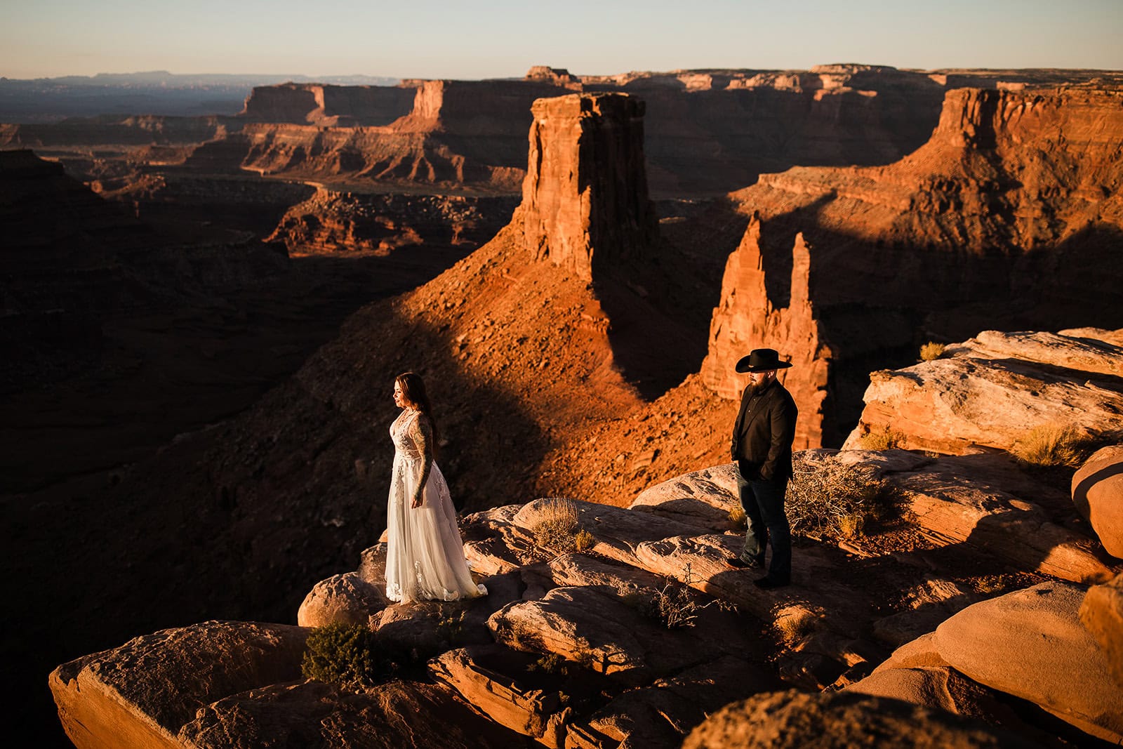 Newlyweds standing at the edge of a cliff in Moab during their wedding in the La Sal Mountains.