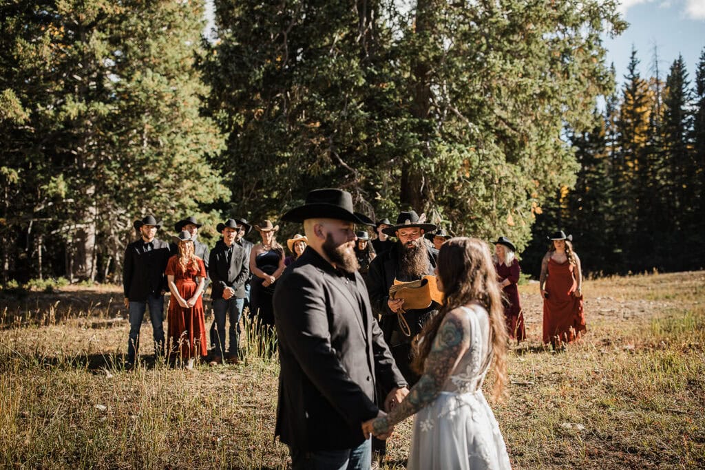 newlyweds holding hands during their wedding ceremony in the La Sal Mountains.