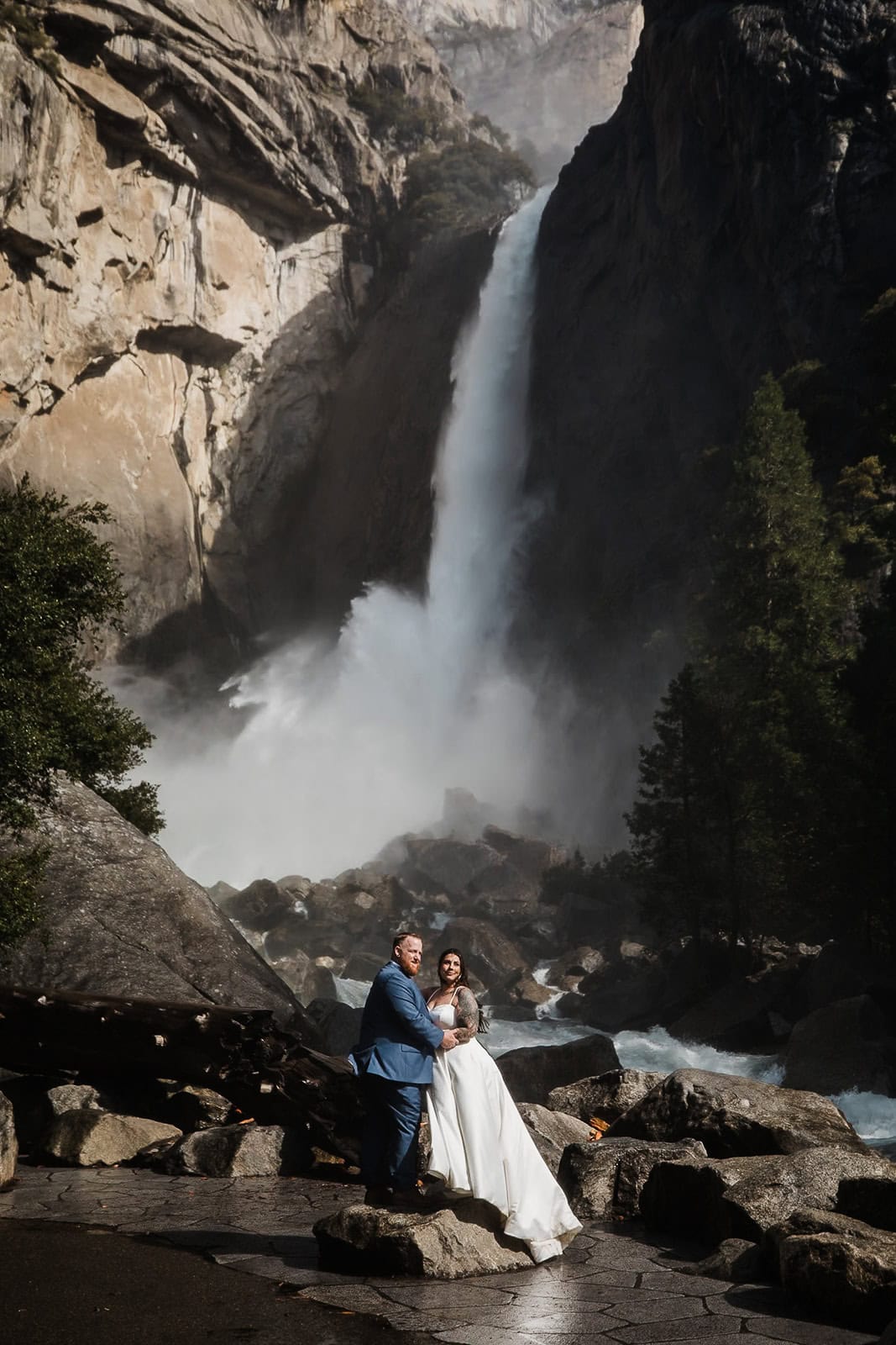 Newlyweds hugging in front of Yosemite Falls, one of the best Yosemite wedding locations.
