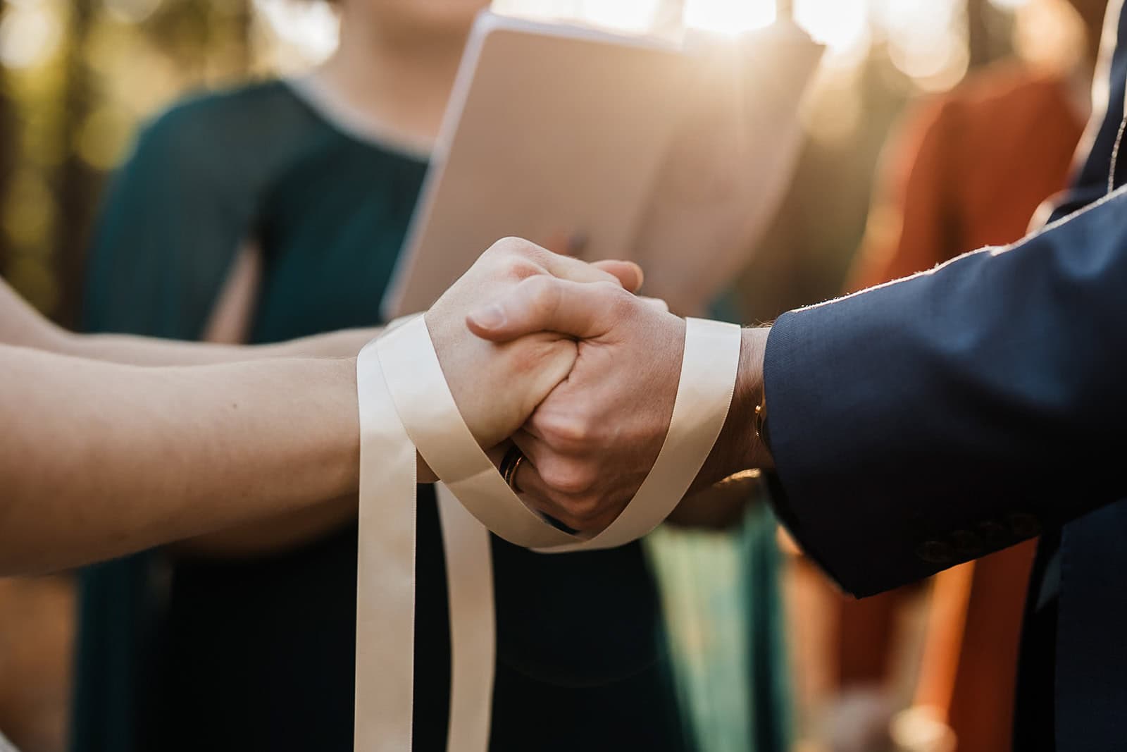 newlyweds holding hands during a hand fasting ceremony.