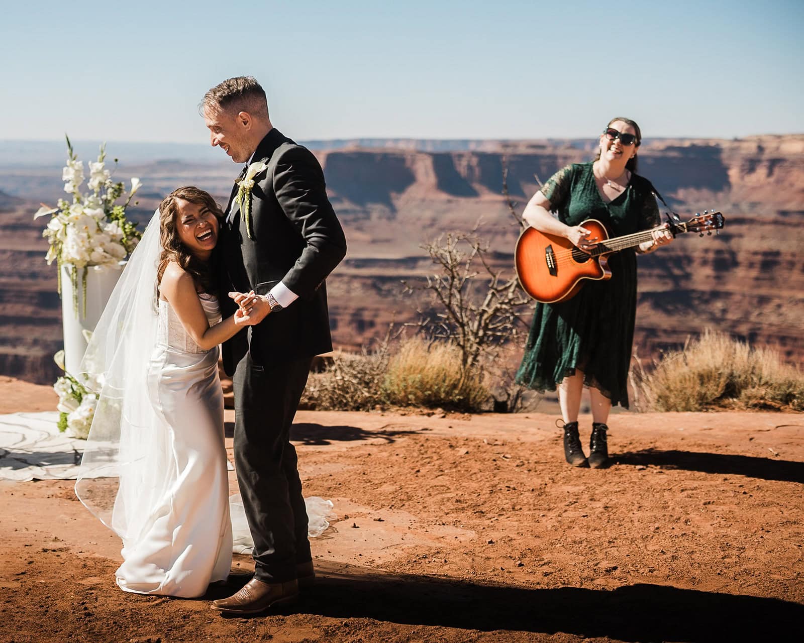 Newlyweds dancing during their elopement ceremony with a friend playing guitar for them.