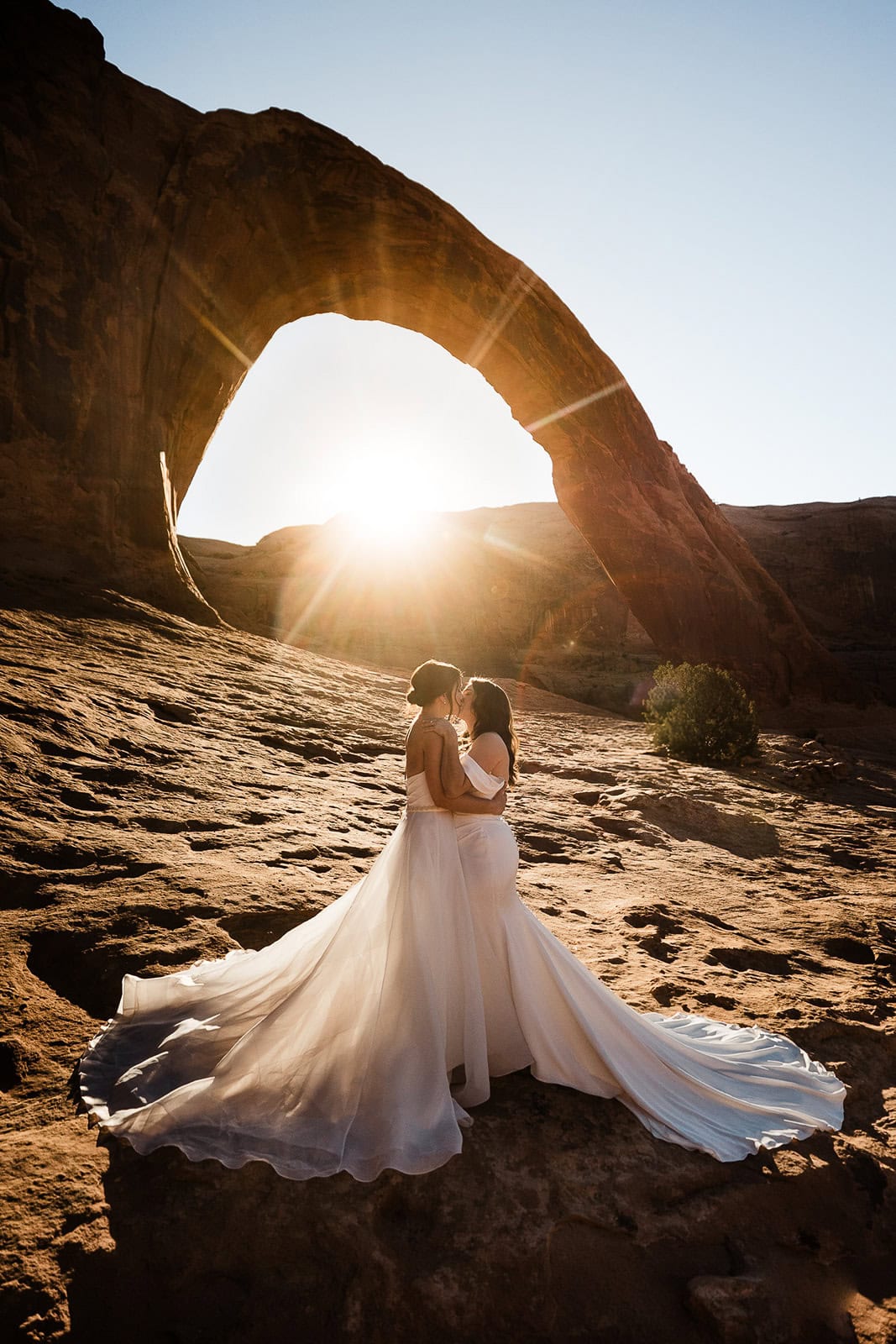 Newlyweds kissing in front of an arch during their elopement ceremony.
